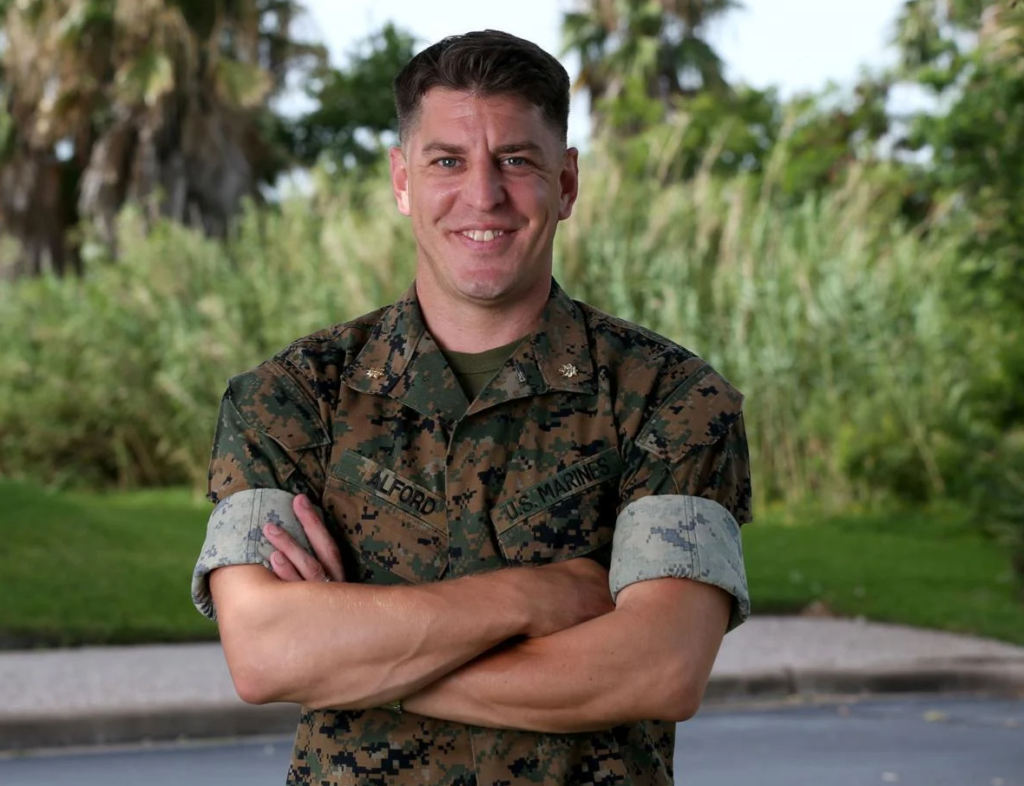 United States Marine Corps Major Veteran Seth Alford Dressed in camo attire arms crossed