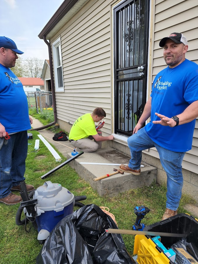 Three men in Rebuilding Together Tee shirts home remodel door trim 