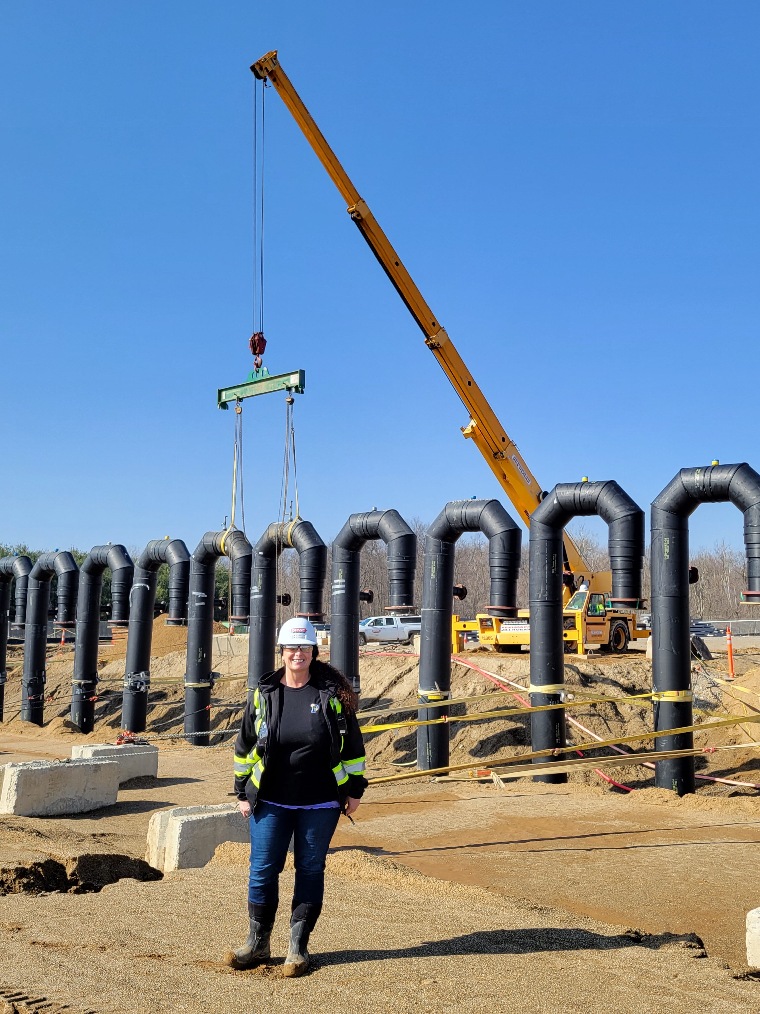 Lisa Wireman in construction uniform standing in front of crane on a job construction site